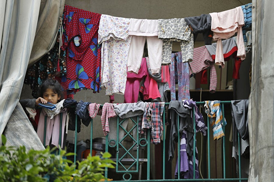 Beyrut'ta pek çok göçmenin bir arada kaldığı, koronavirüs vakalarının görüldüğü kalabalık apartman dairelerinden birinin balkonundan dışarı bakan Suriyeli kız çocuğu.