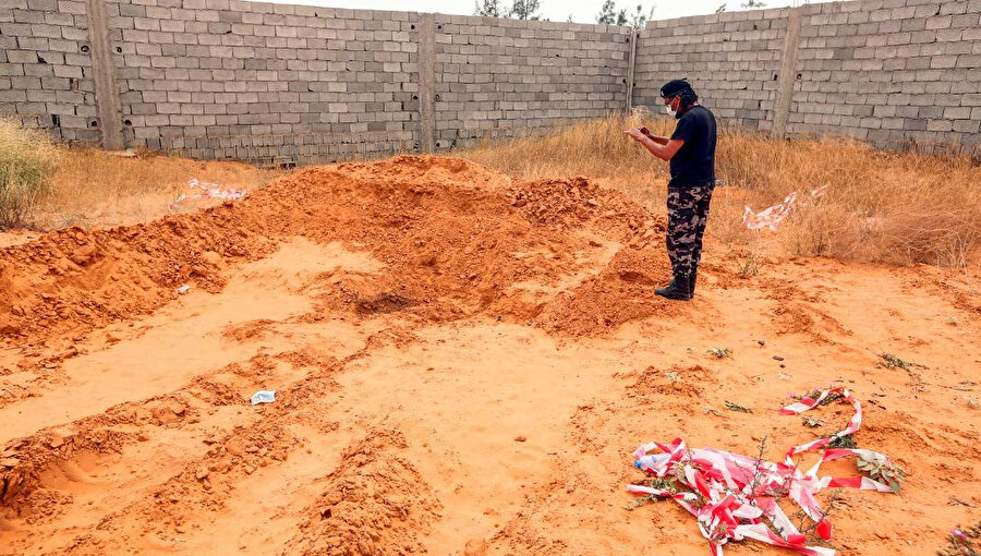 Ulusal Mutabakat Hükümetine bağlı bir güvenlik görevlisi Terhune vilayetinde ortaya çıkarılan bir toplu mezarı fotoğraf çekerken görülüyor.