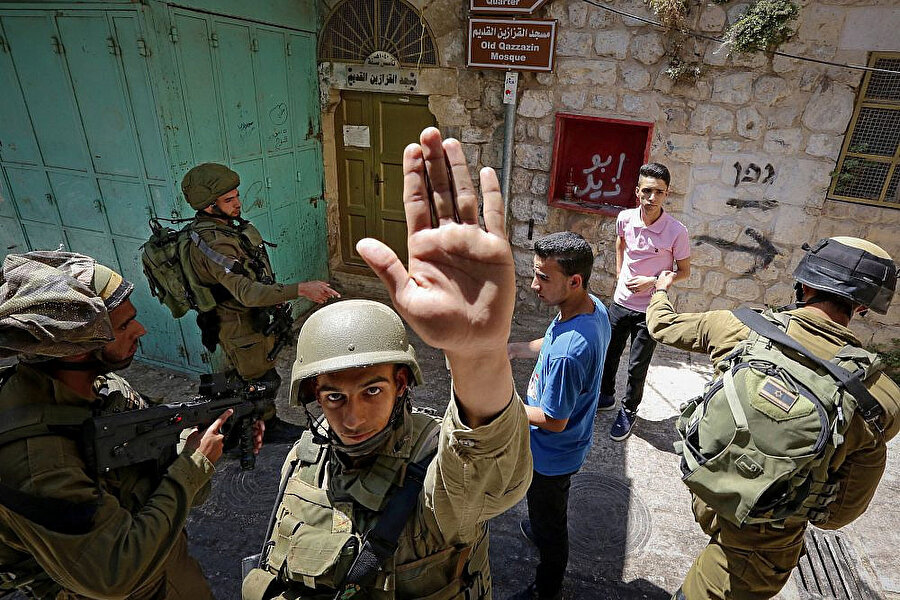 Gazetecilerin görüntü almasını engellemeye çalışan bir İsrail askeri.