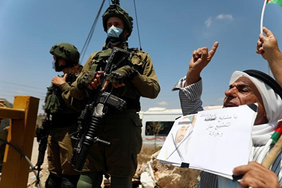 İsrail askerlerinin hemen yanında anlaşmayı protesto eden Filistinliler.