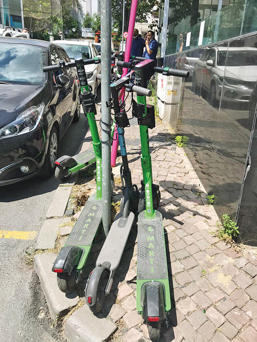 Üst üste kilitlenmiş farklı marka e-scooterlar. 