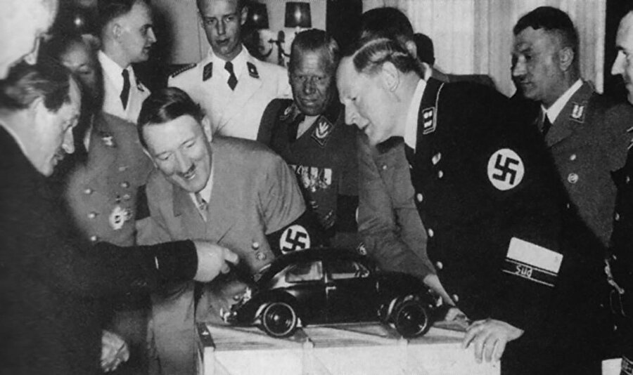 Ferdinand Porsche (en solda modeli işaret eden), Adolf Hitler’e Beetle modelini gösteriyor. 
