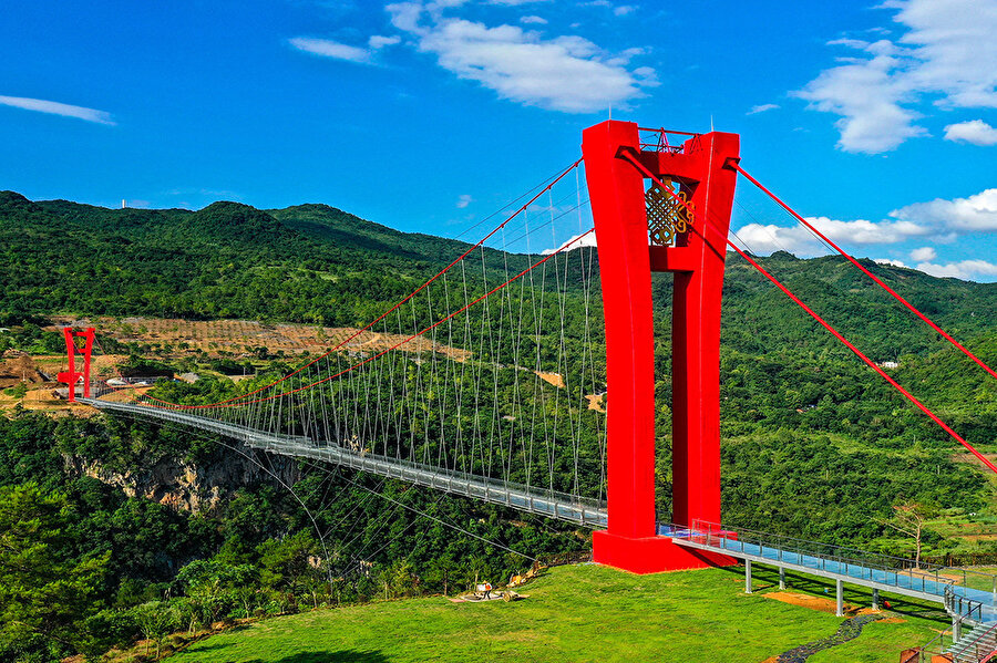 Cam köprü geçidin iki ucundaki kırmızı kulelere asılı.