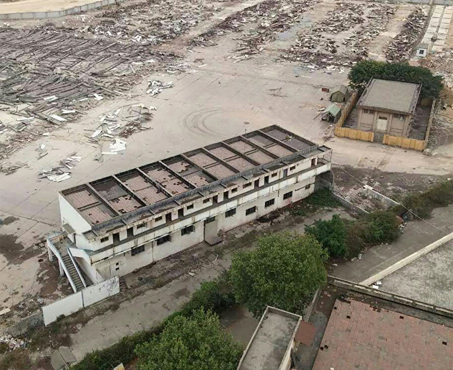 Proje öncesinden, fabrikanın harap olmuş duvarları ve kaldırımının doğa tarafından ele geçirilmiş âtıl hâli. 