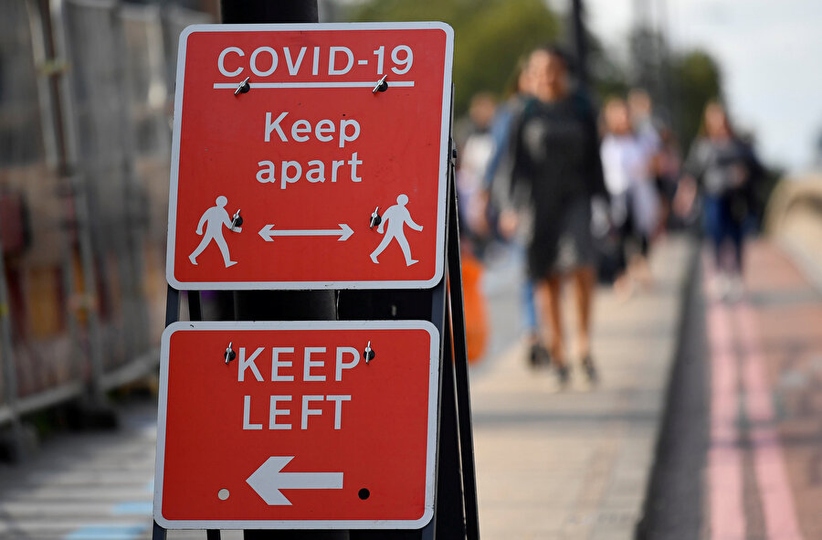 Salgın nedeniyle sosyal mesafeyi düzenleyen 'uzak dur' ve 'soldan git' yazan tabelalar, Londra
