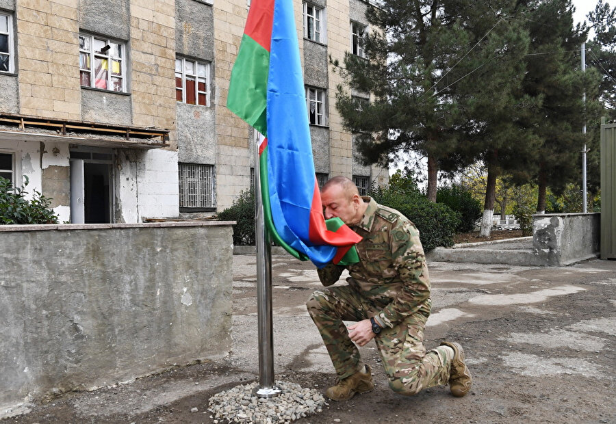 Azerbaycan bayrağını öpen Aliyev, bayrağı göndere çekti.