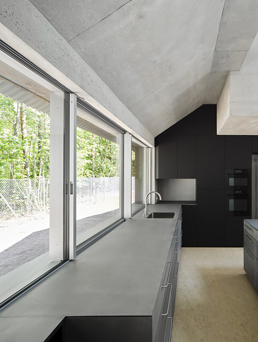 Diğer alanlar gibi, mutfak da geniş pencereler sayesinde dışarısıyla görsel bir bütünlük oluşturuyor.