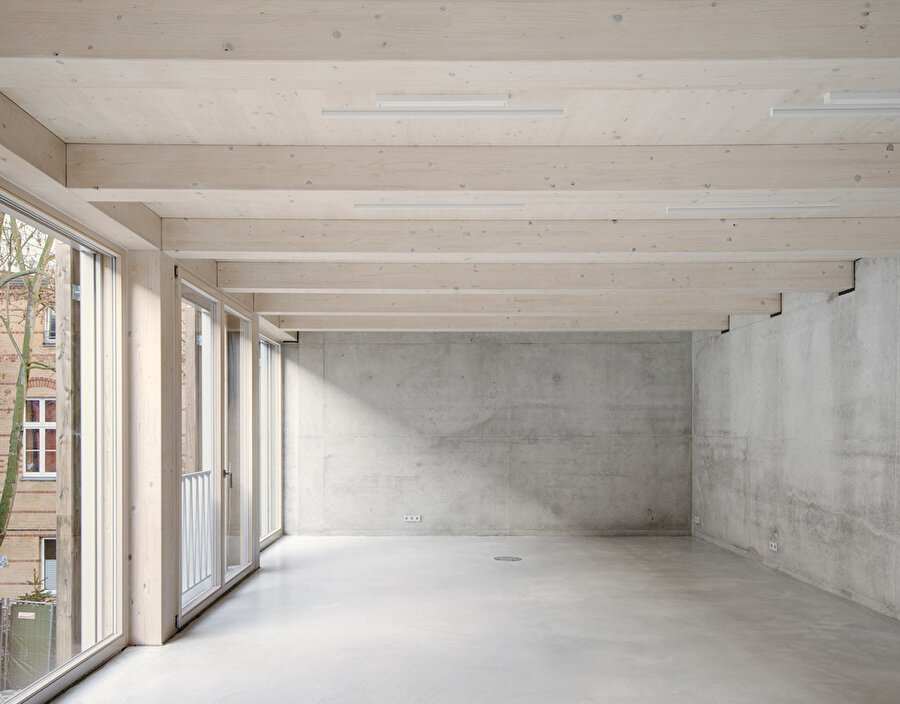 Hibrit yapıdaki ahşap kirişler beton duvarlardaki yuvalara yerleşiyor ve üstlerine yeni katlar inşa ediliyor.