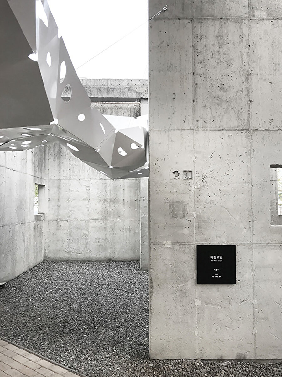 Metal levhalar, brüt beton duvarlarla kontrast oluşturuyor.