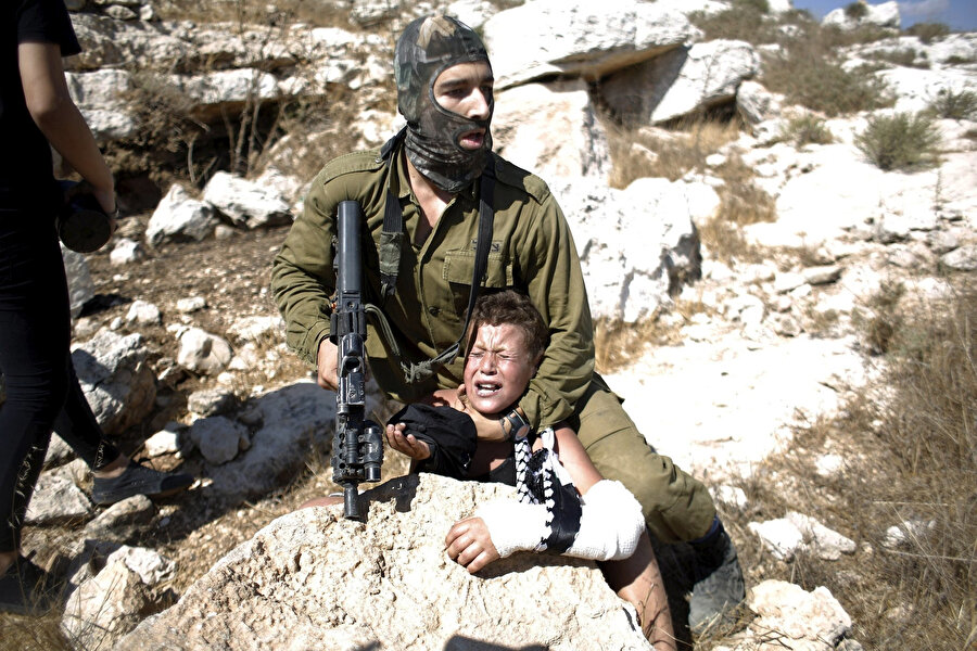 Bir protesto esnasında İsrail askerleri tarafından yaka paça gözaltına alınan Filistinli bir çocuk.