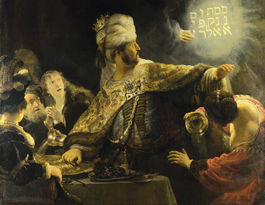  » Duvardaki yazının ürpertici kehaneti: Daniel İncili’ne göre son Babil Kralı Belşazzar, Kudüs’teki Yahudi tapınağında bulunan kutsal altın ve gümüş kâseleri ele geçirir. Böylece altın, gümüş, bronz, demir ve taş tanrılarını memnun edeceğini düşünmektedir. Ancak aniden ortaya çıkan bedensiz bir el, sarayın duvarlarına “Mene, Mene, Tekel, Upharsin” diye yazar. Yani “Nihai son gelmek üzere”. Belşazzar bu ifadeyi krallığının sonunun yaklaştığı şeklinde yorumlar. Rembrandt (1606-1669) ‘Belşazzar’ın Şöleni’ isimli tablosunda bu olayı tasvir etmektedir.  