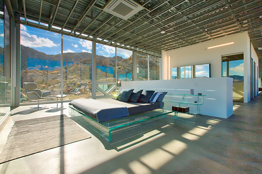 Invisible House’da, cam bir yatak bulunuyor. Cam yatak odaya estetik ve modern bir hava kazandırıyor. 