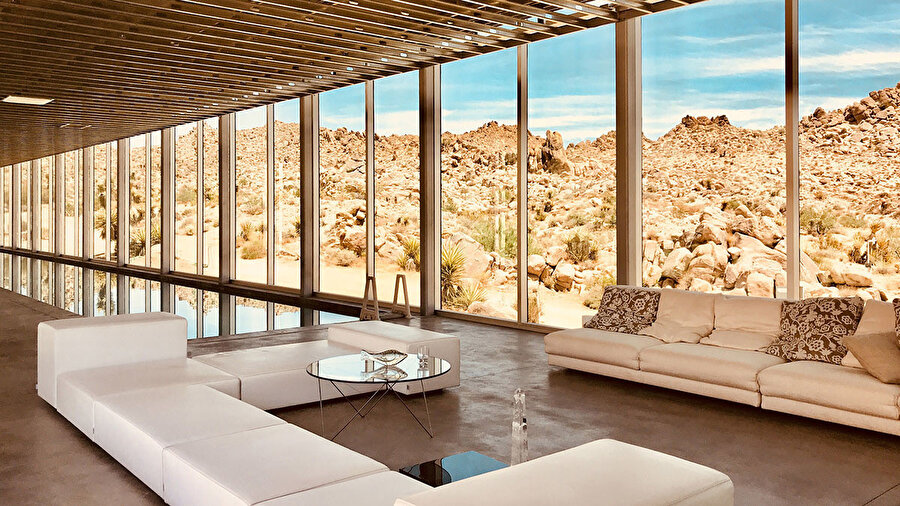 Pürüzsüz beton zeminler ve modern koltuklar, parlayan cam yüzeylerle bir bütün oluşturuyor.