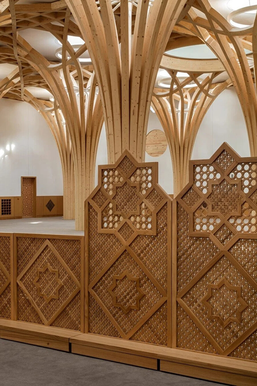 Erkek ve kadın ibadet alanları, İslami geometrik desenlerden oluşan ahşap seperatörlerle ayrılıyor.