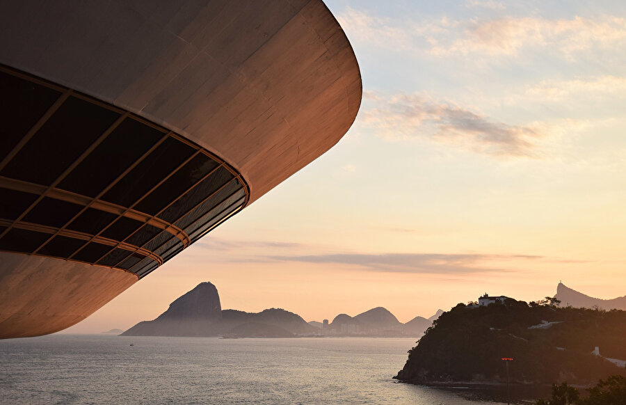 Müzenin pürüzsüz kıvrımları, Rio de Janeiro'nun dağlık coğrafyası ile kontrast oluşturuyor.