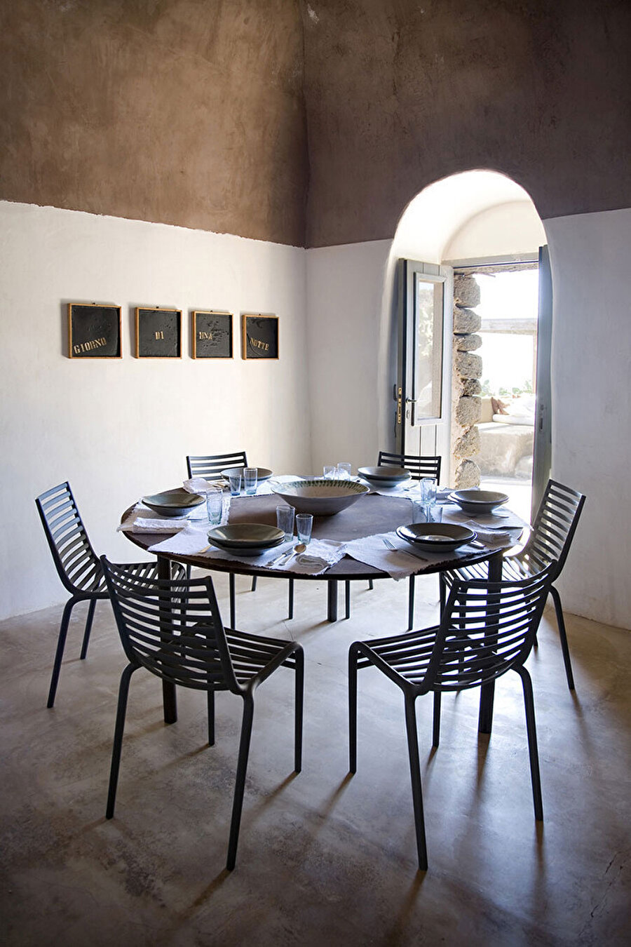 Mutfakta yuvarlak masanın etrafında, Starck'ın Driade imzalı pip-e sandalyeleri ve duvarda Luigi Stoisa'na ait bir çalışma bulunuyor.