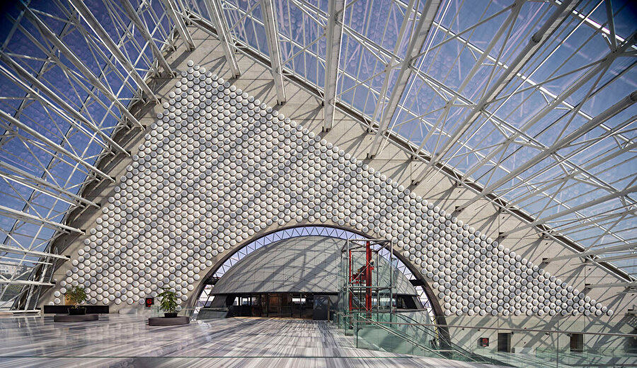 Üçgen prizmatik kütlede çatı ve cephe ayrımının olmadığı geçirgen üst örtü, mekan içindeki iklimsel deneyimlerin ortaya çıkmasına olanak sağlıyor.