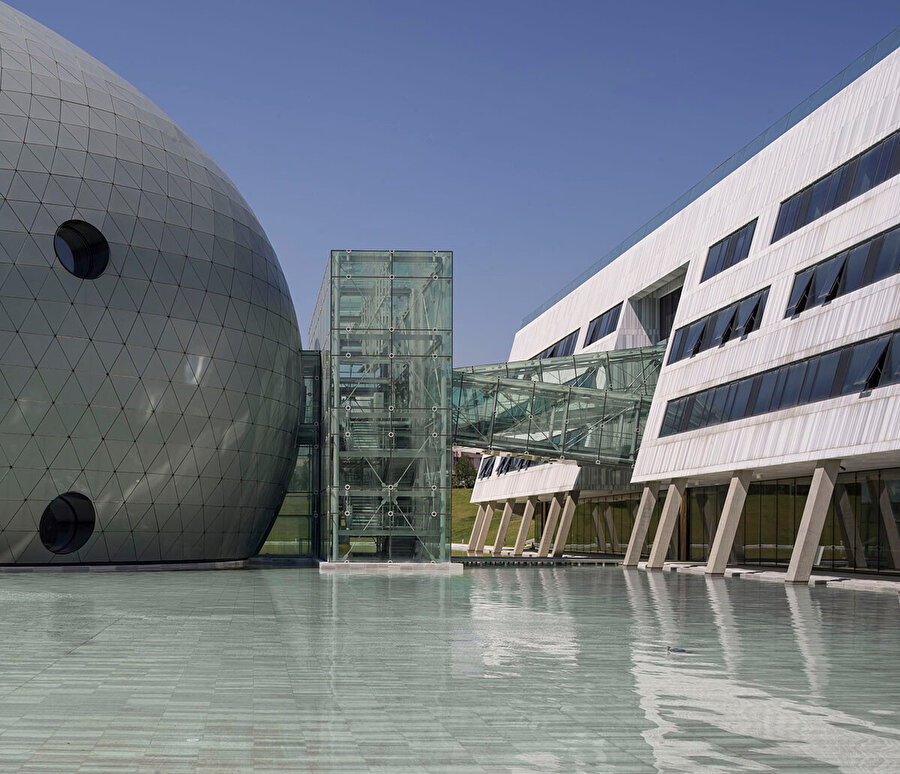 Kütleleri çevreleyen dörtgen havuz, farklı mevsim ve günün farklı saatlerinde tüm kurguyu ters yöne çevirerek yeni bir tasvir oluşturuyor.