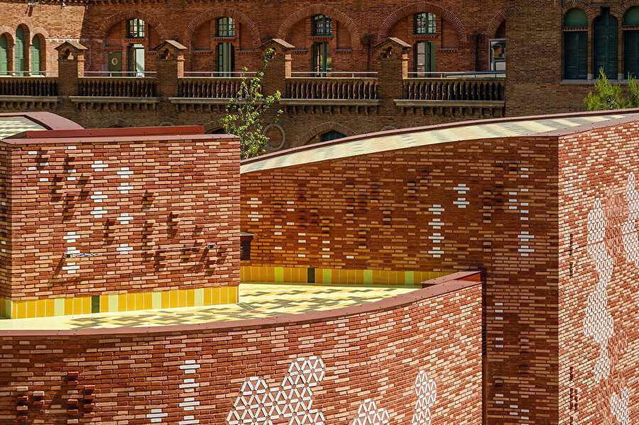  Bina cephesi, çeşitli renk ve doku kompozisyonlarında bir araya getirilmiş, sırlı seramik eklentilere sahip bir tuğla duvardan oluşuyor. Çatı ise yeşil seramiklerle kaplanıyor.