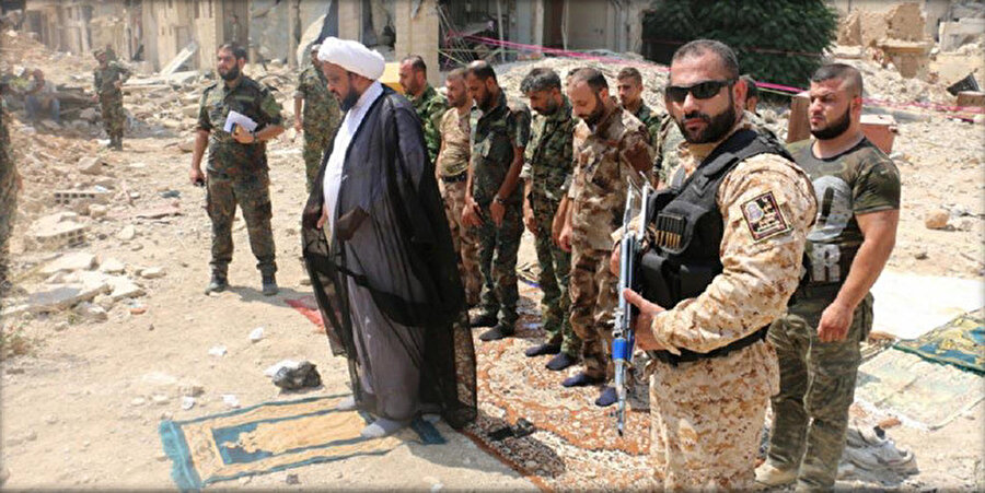 Irak menşeli Şii milis örgütü en-Nücebâ’nın lideri Ekrem el-Ka’bî’yi, Şam yakınlarında bir bölge olan harap vaziyetteki Dâriyye’de resmeden bir fotoğraf. Hamaney’e yakın bir isim olduğu bilinen el-Ka’bî’nin Suriye’deki demografik yapıyı şiiler lehine değiştirme yönünde faaliyetler yaptığı biliniyor.