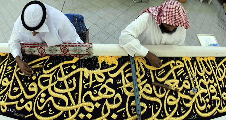 Mekke'deki kisve fabrikasında Kabe'yi örtmek için siyah kisveye altın iplikle İslami Arapça hat işleyen zanaatkarlar.