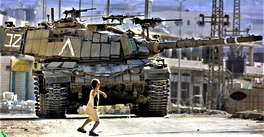 Filistinli bir çocuk, İkinci İntifada sırasında Faris Odeh'in ikonik görüntüsüne çok benzer şekilde İsrail Savunma Kuvvetleri'ne ait bir tanka taş atıyor.