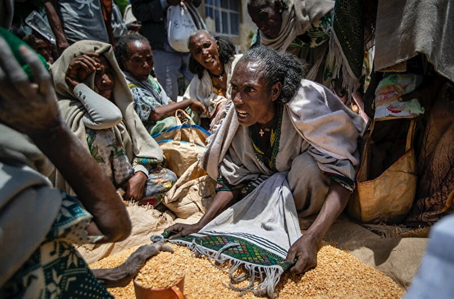 Etiyopyalı bir kadın, kuzey Etiyopya'nın Tigray bölgesindeki Agula kasabasında yardım derneği tarafından dağıtılan sarı bezelyeyi bölüştürme konusunda başkalarıyla tartışıyor, 8 Mayıs 2021.