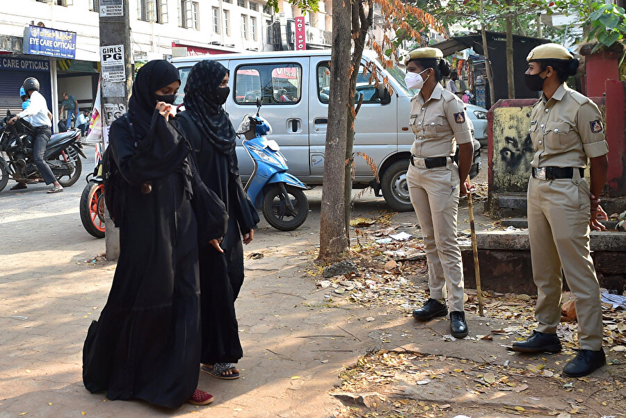 Hindistan'ın güney eyaleti Karnataka'nın Udupi kasabasında başörtülü kız öğrenciler, son başörtüsü yasağının ardından polis memurları okulun önünde nöbet tutarken derslere katılmak için geliyor.