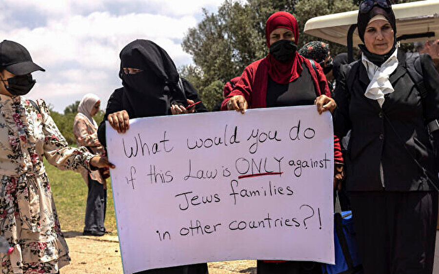 İsrailli Arap kadınlar, Kudüs'teki protestolar sırasında "Bu yasa sadece diğer ülkelerdeki Yahudi ailelere karşı olsaydı ne yapardınız?" yazılı afiş taşıyor, 5 Temmuz 2021.
