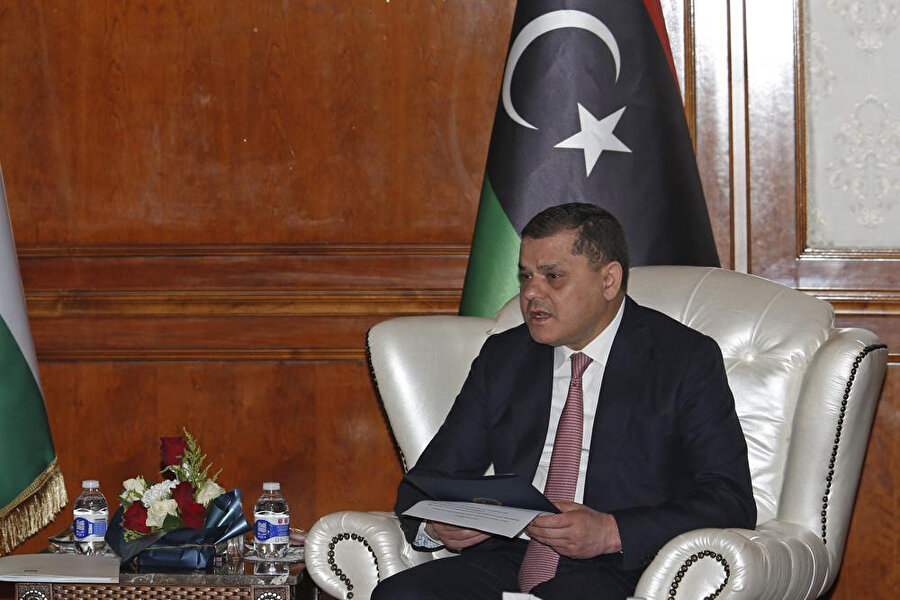 Başbakan Dibeybe, 14 Şubat 2022 Pazartesi, Libya'nın Trablus kentindeki başbakanlık merkezinde bir Libya bayrağının önünde oturuyor. Kanada'dan mühendislik alanında üniversite diplomasına sahip olan Dibeybe, diğerlerine kıyasla nispeten siyasi bir acemi. (AP fotoğrafı/Yousef Murad)