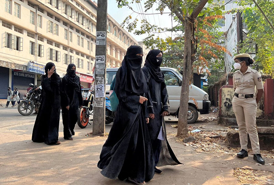 Hindistan'ın güney eyaleti Karnataka'nın Udupi kasabasında başörtülü kız öğrenciler, Karnataka'daki Udupi kasabasında başörtüsü yasağının ardından, polis memurları okulun önünde nöbet tutarken derslere katılmak için geliyor, 16 Şubat 2022.