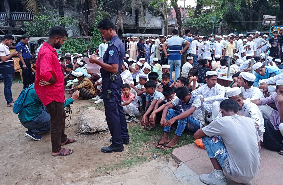 Bangladeşli bir polis, Cox's Bazar'daki plajda gözaltına alınan Rohingyalı mültecilerin bilgilerini alıyor.