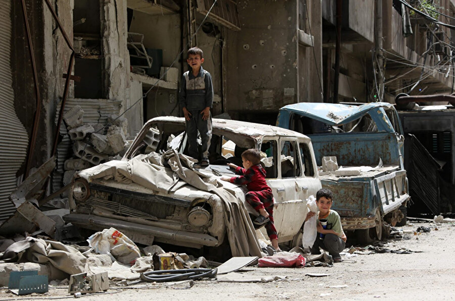 Şam'ın eteklerinde, muhaliflerin elindeki Duma'da tahrip olmuş bir arabada oynayan Suriyeli çocuklar. 
