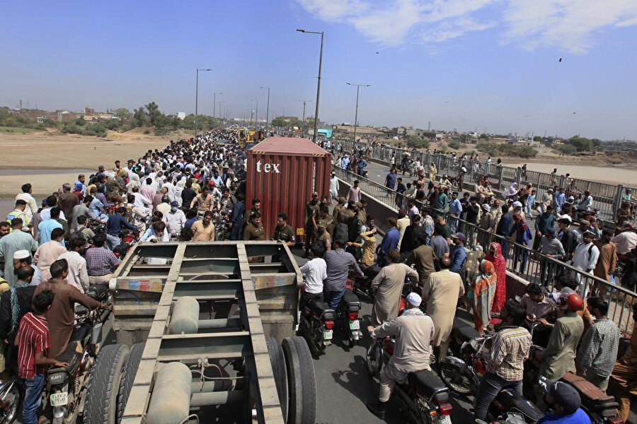 Pakistan'ın Lahor kentinde ana muhalefet partisinin planlanan protestosunu engellemek amacıyla yetkililer tarafından yerleştirilen nakliye konteynerleri nedeniyle trafiğe kapatılan Ravi Nehri üzerindeki köprüden geçen halk.