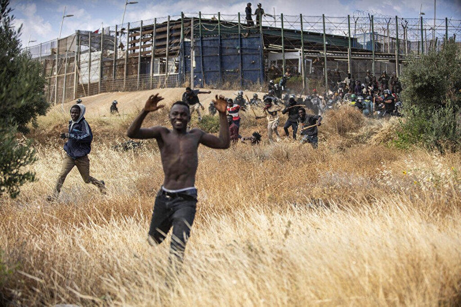 AP - Javier Bernardo | Göçmenler, İspanya'nın Melilla yerleşim bölgesini Fas'tan Melilla'daki Fas'tan ayıran çitleri geçtikten sonra İspanyol topraklarında koşuyor. İspanya, Cuma, 24 Haziran 2022.