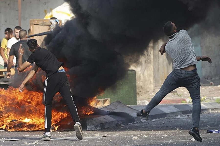 Filistinli protestocular, işgal altındaki Batı Şeria'daki eski Nablus kasabasına 9 Ağustos 2022'de düzenlenen baskının ardından İsrail güçlerine taş atıyor. (AFP)