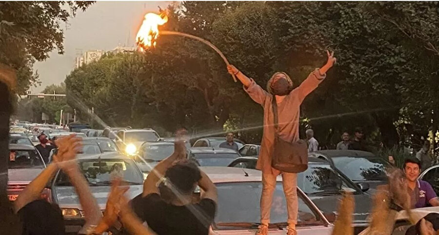 Pazartesi günü Tahran'daki protestolar sırasında başörtüsünü ateşe veren bir kadın.