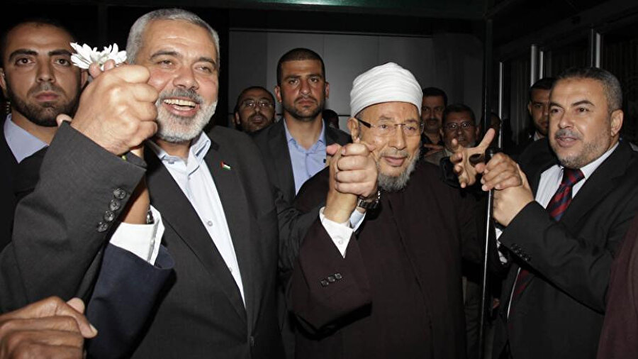 Hamas lideri İsmail Heniye, 8 Mayıs 2013'te, güney Gazze Şeridi'ndeki Refah Kapısı'na gelen Karadâvî'yi karşılarken. Karadâvî, 2013 yılında Müslüman âlimlerden oluşan bir heyetle Gazze Şeridi'ne üç günlük bir ziyaret için gelmişti.