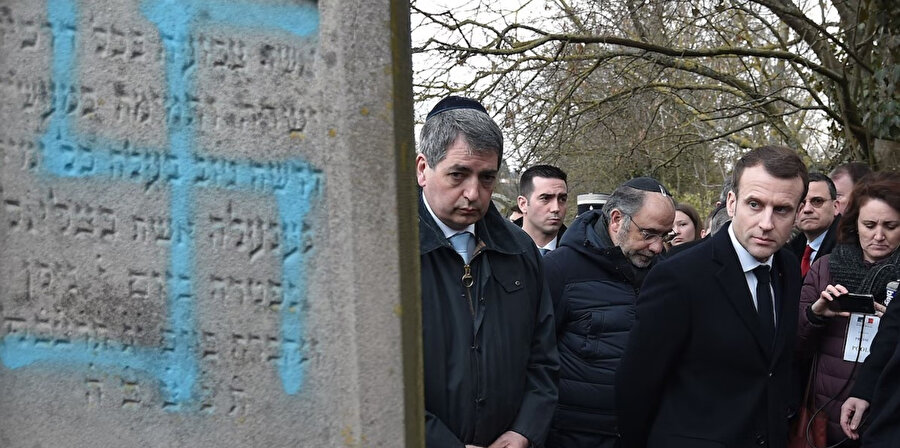 Fransa Cumhurbaşkanı Emmanuel Macron, Fransa'nın Quatzenheim kentinde, düzinelerce mezarın gamalı haçlarla tahrip edildiği bir Yahudi mezarlığını ziyaret ederken.