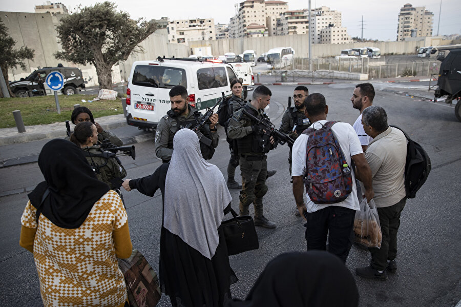 Ordu baskını sırasında nöbet tutan İsrail güçleri, sivillerin geçişine müdahale ediyor.
