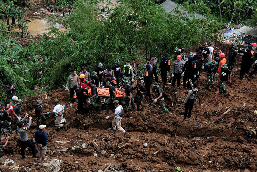Depremin neden olduğu toprak kayması alanından insanları tahliye eden Endonezyalı kurtarma ekipleri. 