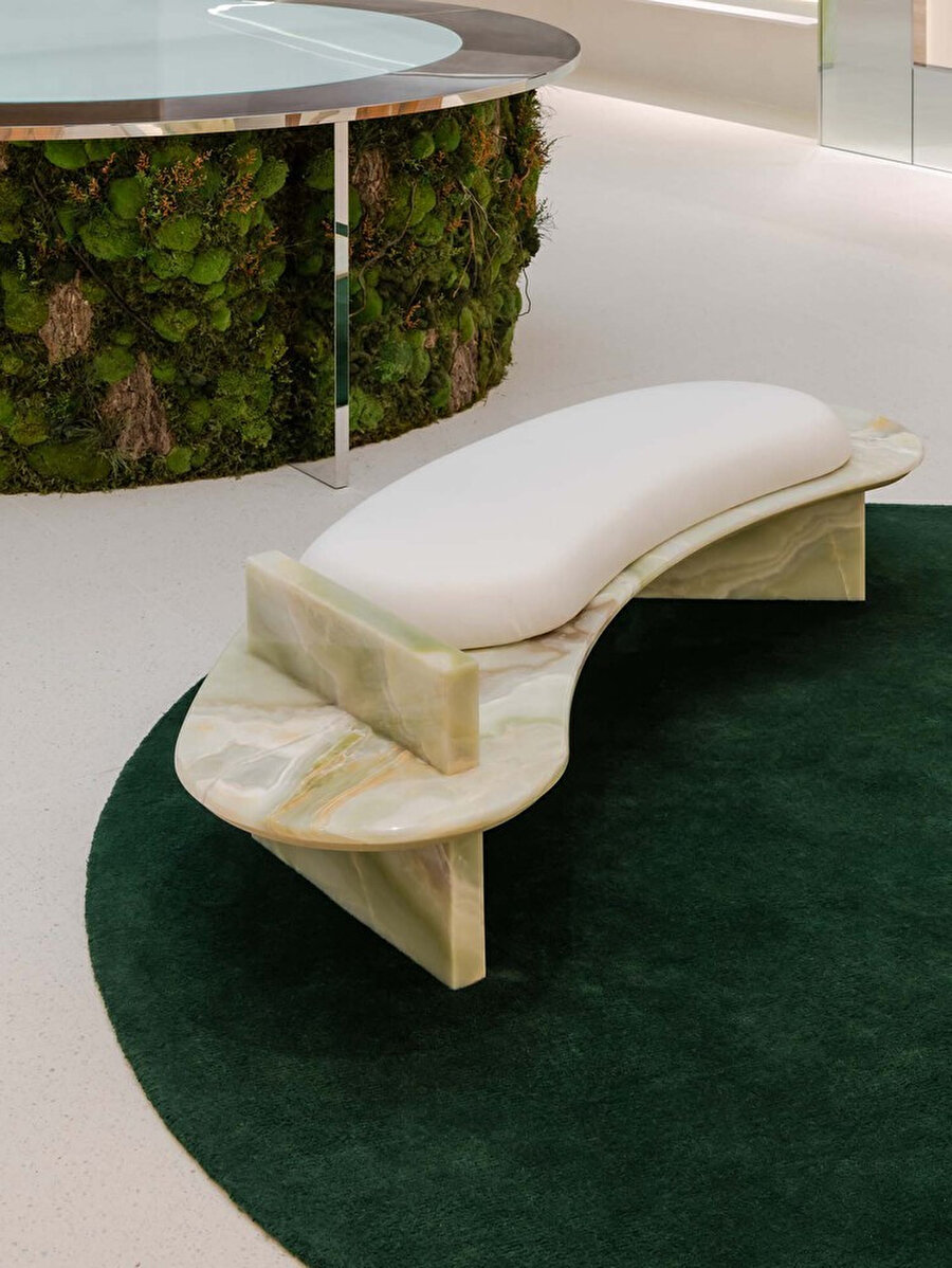 Yeşil oniksten imal edilen uzun kavisli bir bank ve meşe koltuk, mağazanın konseptiyle uyum yakalıyor.