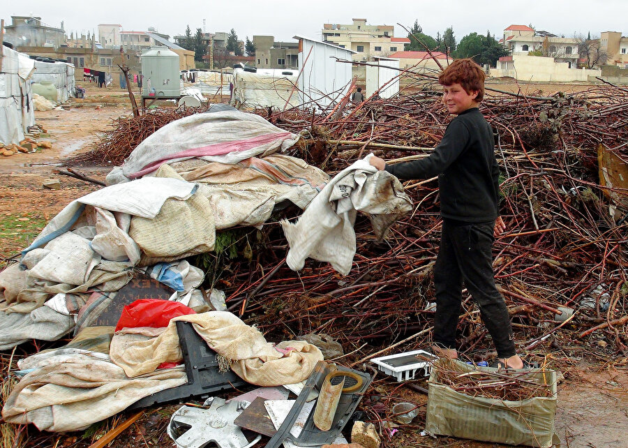 Suriyeli çocuk ısınabilmeleri için çöplerden yakacak şeyler topluyor.