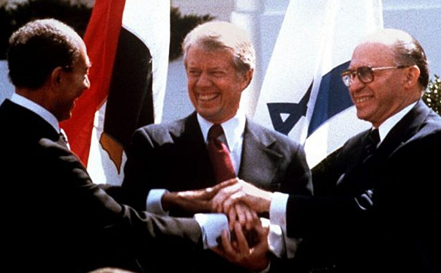 Mısır Devlet Başkanı Enver Sedat (solda), ABD Başkanı Jimmy Carter (ortada) ve Başbakan Menachem Begin, Mısır ile İsrail arasındaki barış anlaşmasını imzaladıktan sonra Beyaz Saray'ın bahçesinde el sıkışıyor.
