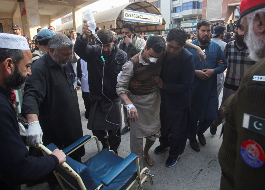Pakistan'ın Peşaver kentindeki bir camide meydana gelen intihar saldırısının ardından sağlık ekibi ve halk, yaralılara yardım ediyor.