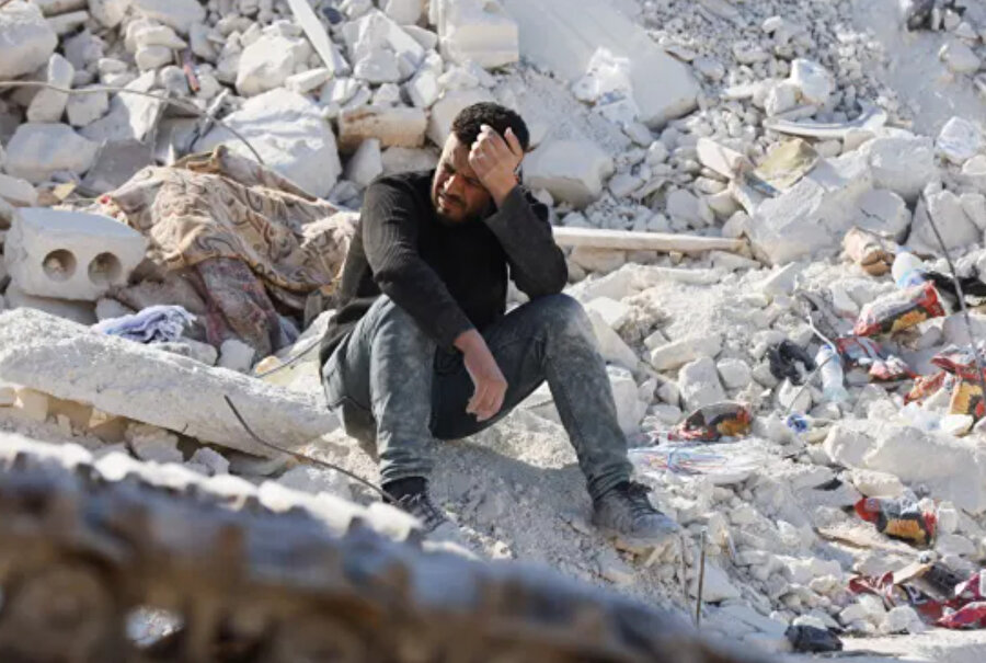 Bir adam, Suriye'nin İdlib vilayetinin isyancı kontrolündeki Harem kasabasında bir zamanlar akrabalarının yaşadığı bir evin yıkıntıları üzerinde oturuyor.