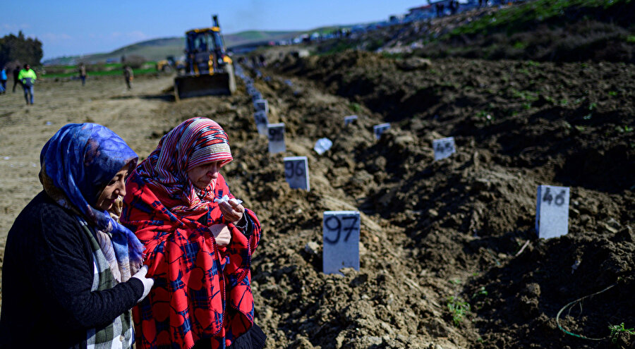 Kadınlar, Hatay'daki bir mezarlıkta depremzedelerin yasını tutuyor.