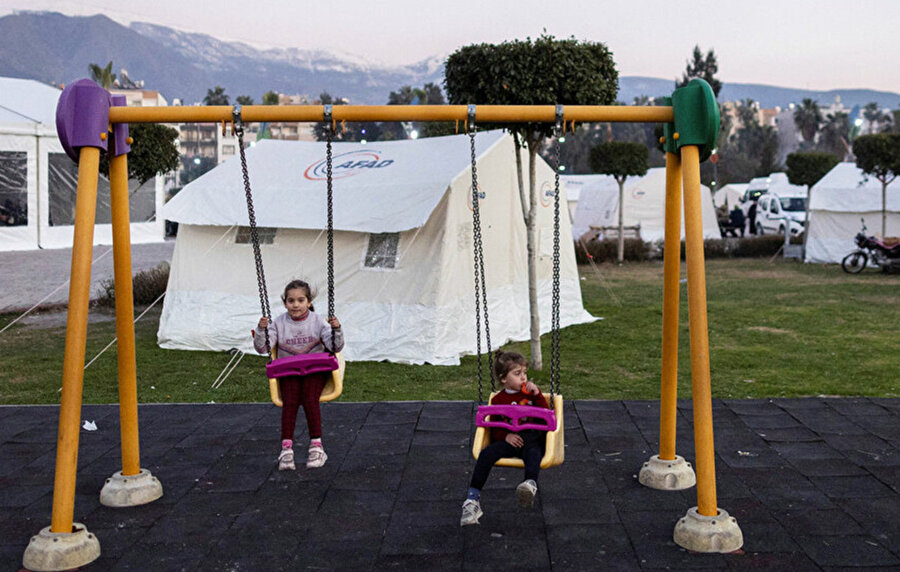 Depremin ardından İskenderun'da yerinden edilmiş kişiler için kampa dönüştürülen parkta çocuklar oyun oynuyor.