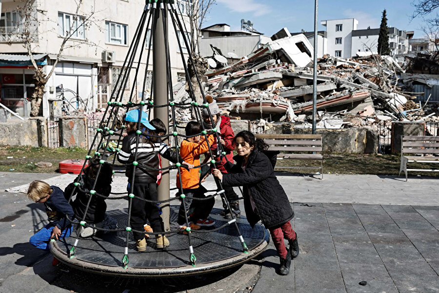 Adıyaman'da depremden etkilenen insanlara destek olmak için kurulan geçici barınma merkezinin parkında çocuklar oynuyor.