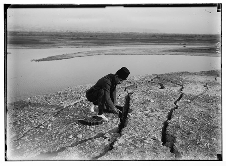 Amerikan Kolonisi fotoğrafçılarına eşlik eden bir görevli, Ölü Deniz'de 1927 depreminin neden olduğu bir yarığın boyunu tüfeğiyle ölçerken.